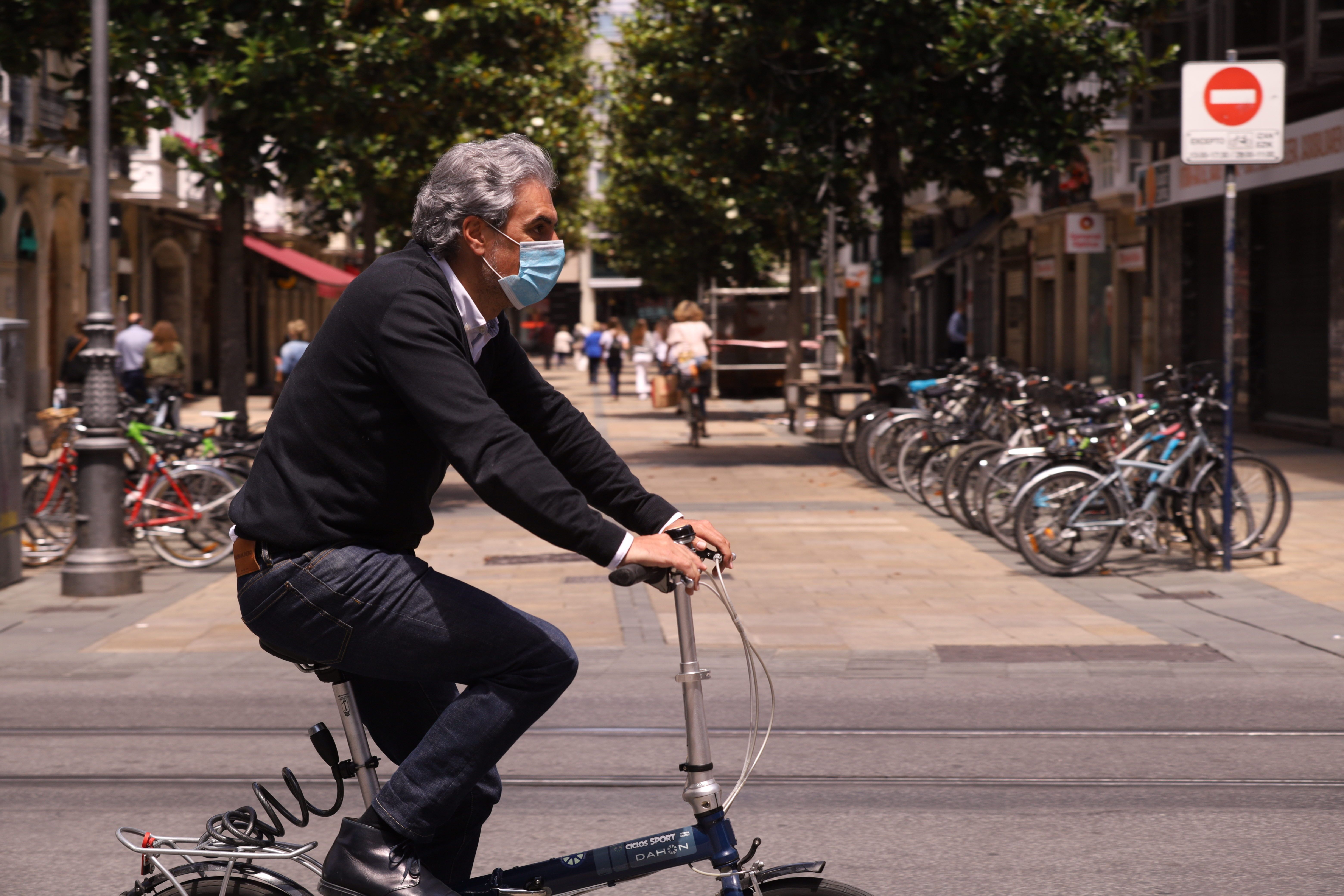 Un hombre pasea en bicicleta con mascarilla por una céntrica calle de Vitoria