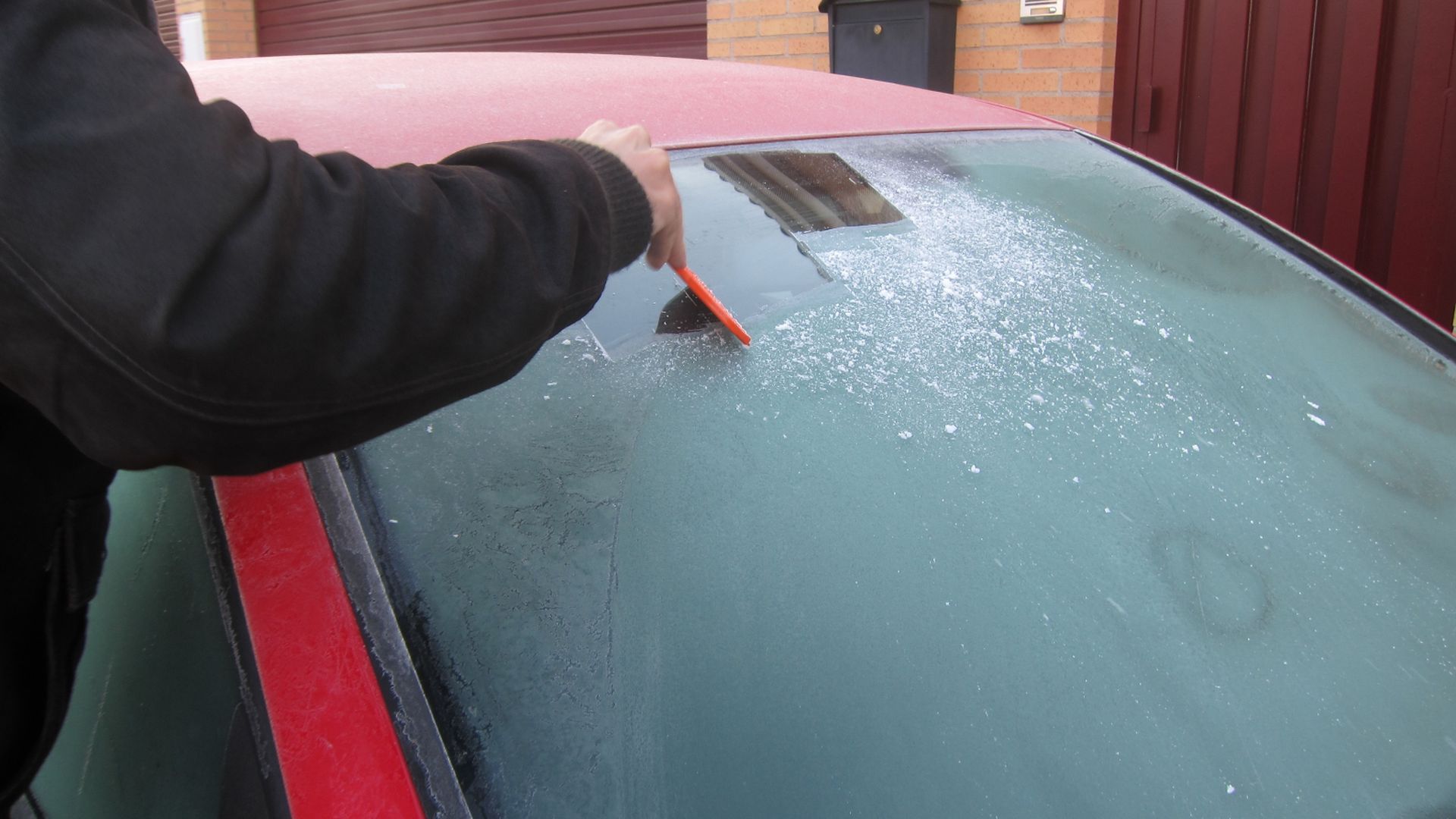 Una persona retirando la escarcha de su coche
