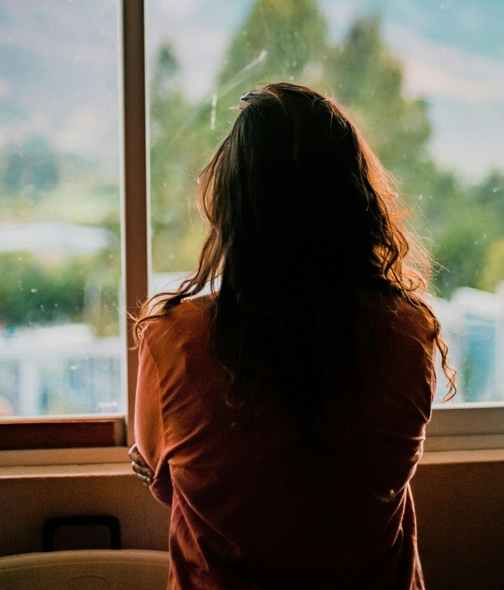 Una mujer de espaldas mirando por la ventana