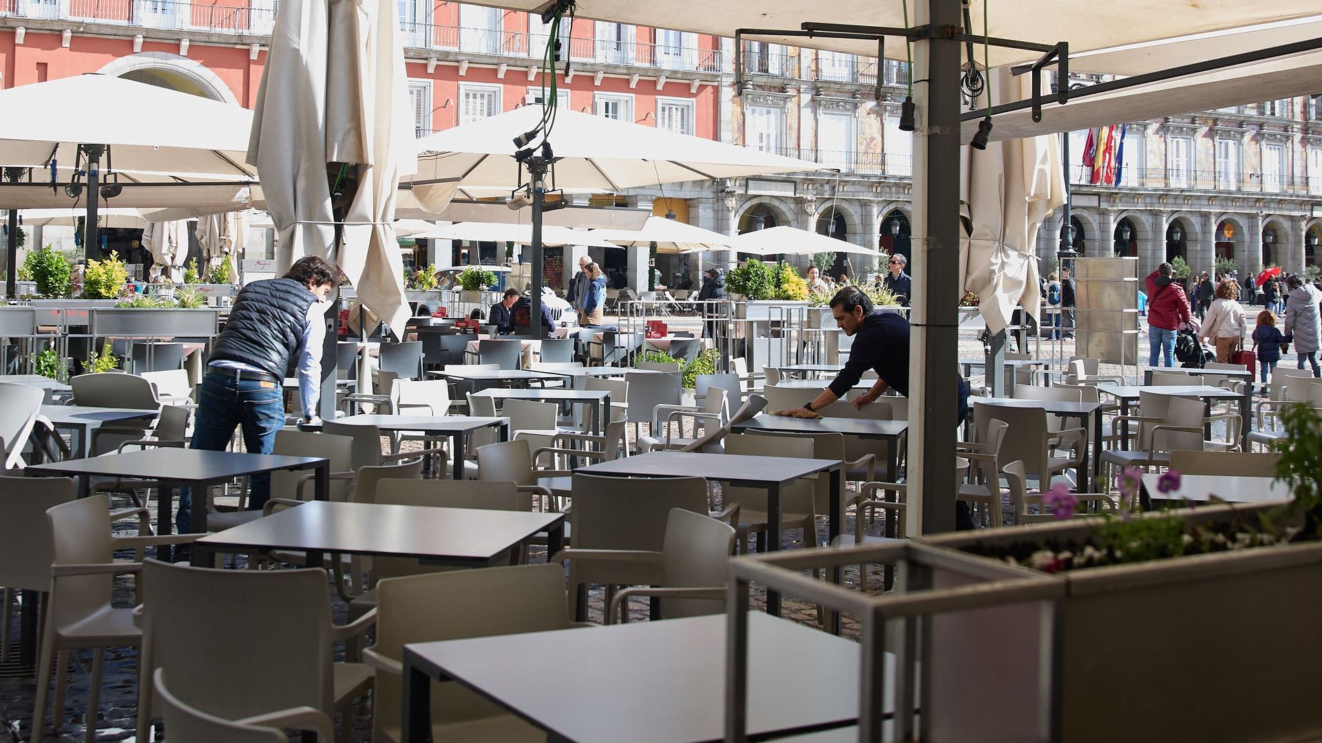 Dos trabajadores preparando la terraza de un bar en la plaza Mayor de Madrid Dos trabajadores preparando la terraza de un bar en la plaza Mayor de Madrid