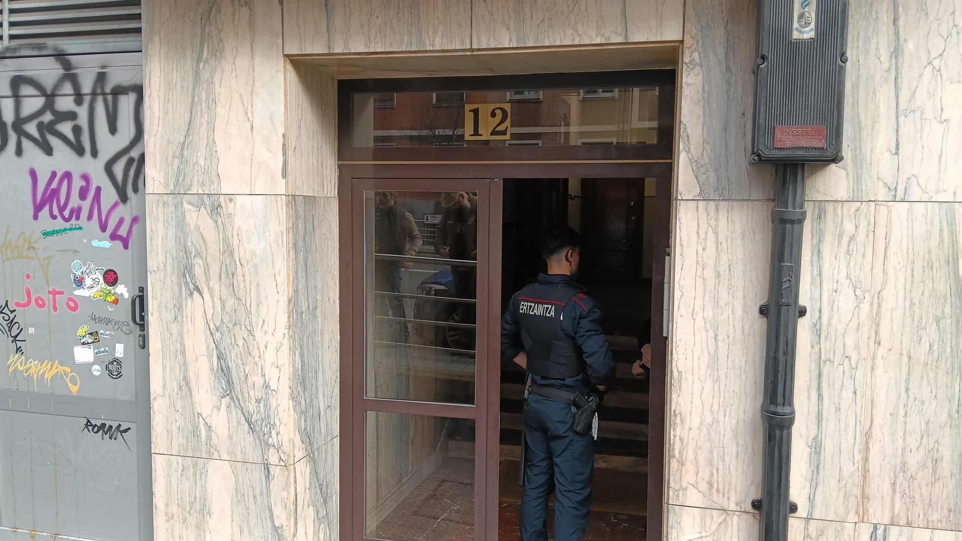 Un ertzaina custodia la entrada al bloque que permanecía acordonado mientras trabajaba la Policía Científica