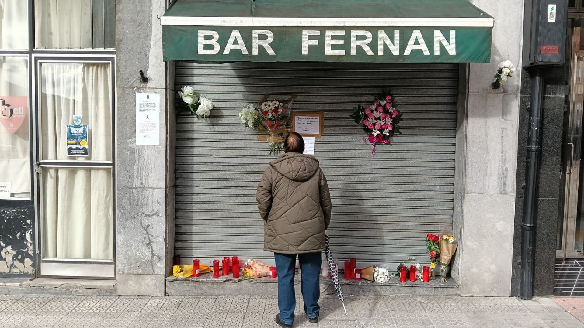Una vecina se detiene a leer las notas colocadas en la persiana del bar que regentaba Luis, en la calle Trauko