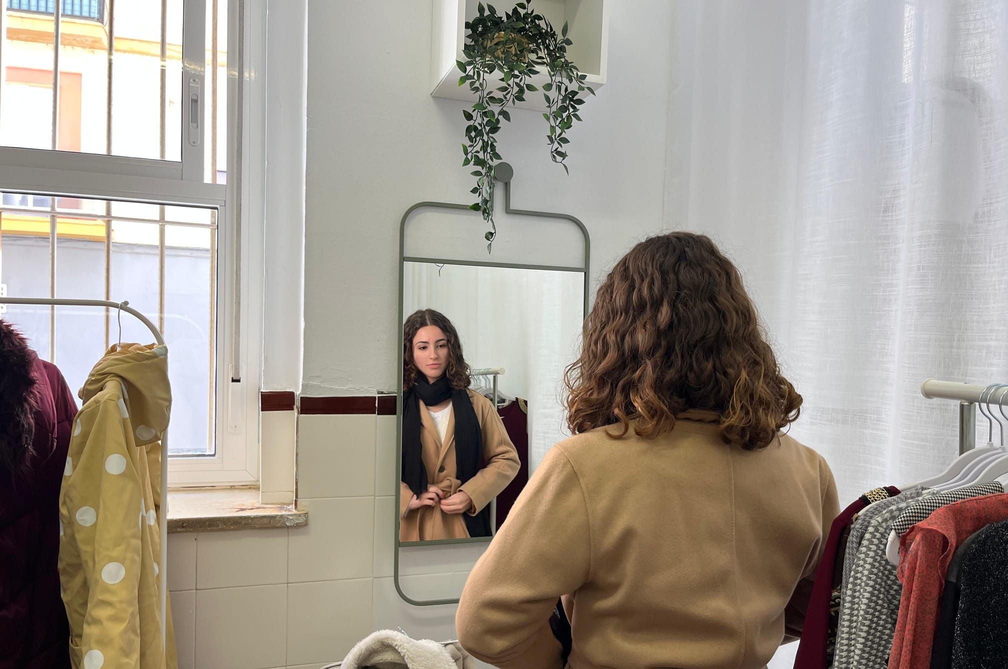 Una chica viendo cómo le queda una chaqueta en la estrenada tienda