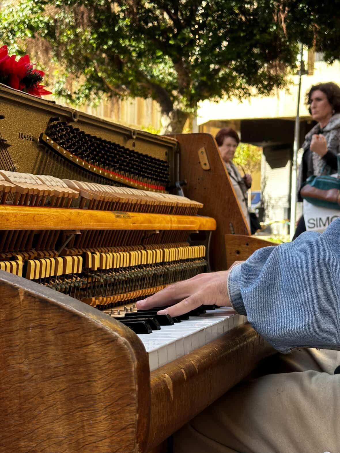 Max tocando su piano de madera ante la mirada de vecinos de Almería