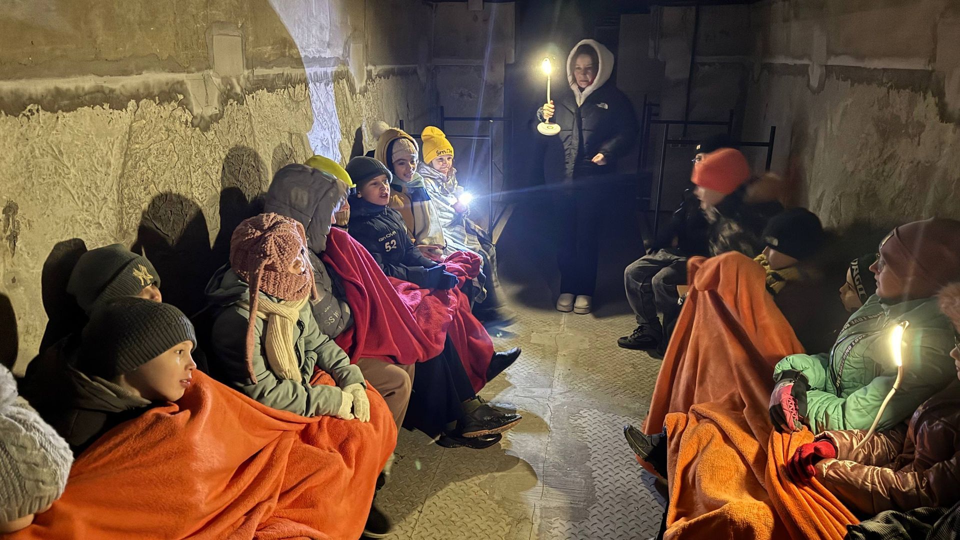 Un grupo de niños y niñas, junto a una trabajadora de Aldeas Infantiles SOS, en un refugio antiaéreo durante un bombardeo Un grupo de niños y niñas, junto a una trabajadora de Aldeas Infantiles SOS, en un refugio antiaéreo durante un bombardeo