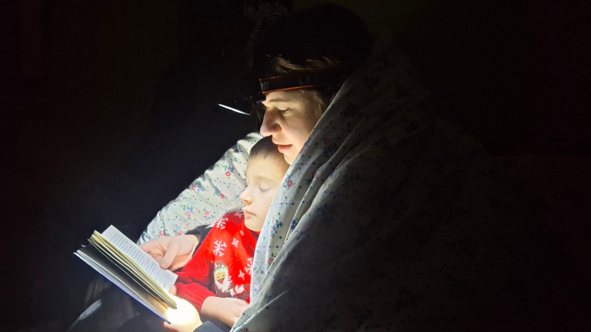 Una madre lee a su hijo durante un apagón