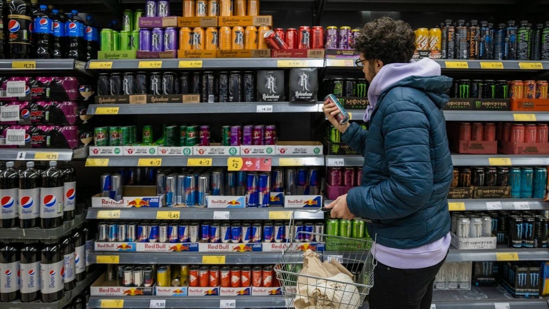 Un joven mira la sección de bebidas energéticas en el supermercado. Un joven mira la sección de bebidas energéticas en el supermercado.
