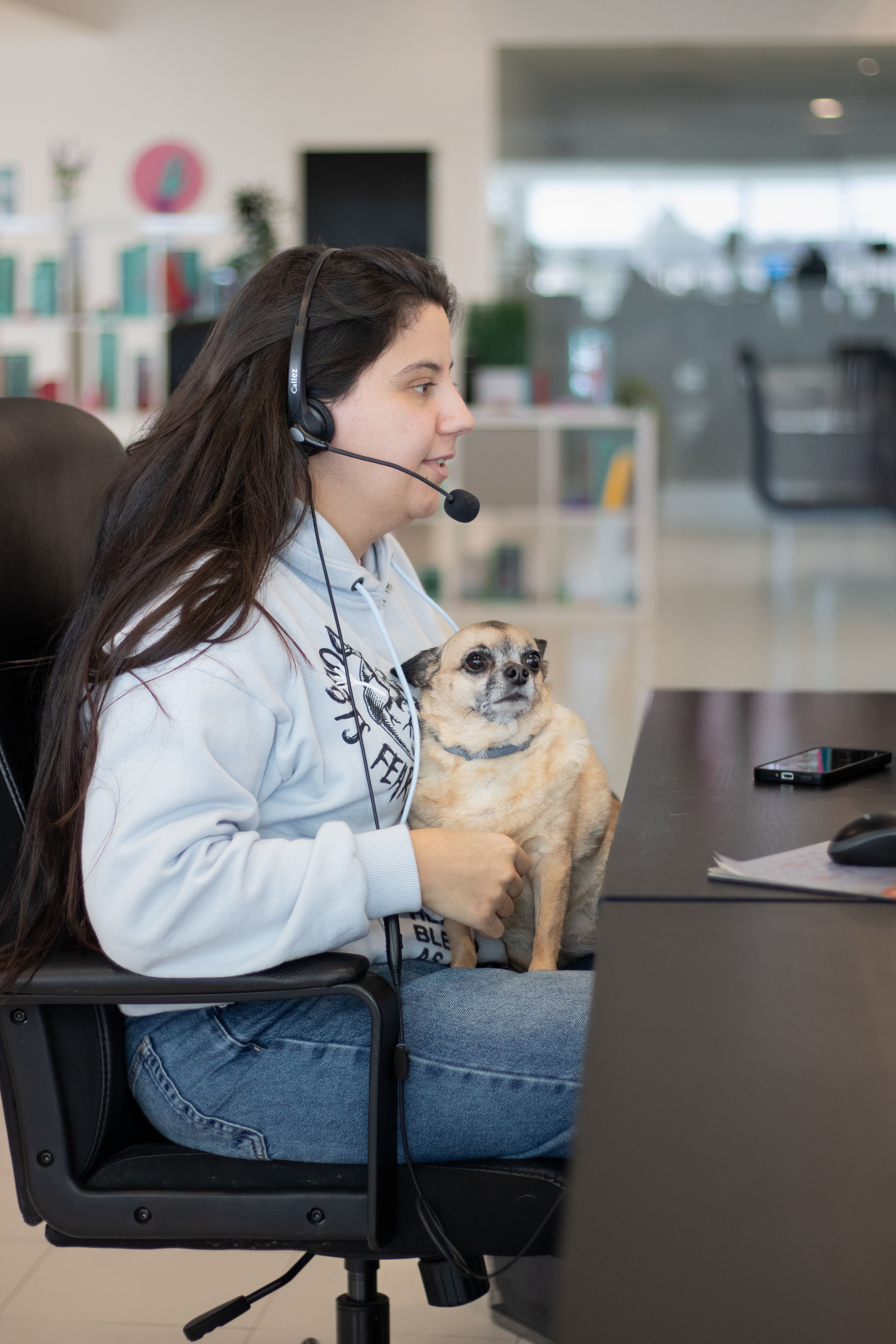 Una empleada atiende a un cliente mientras sostiene a su perro