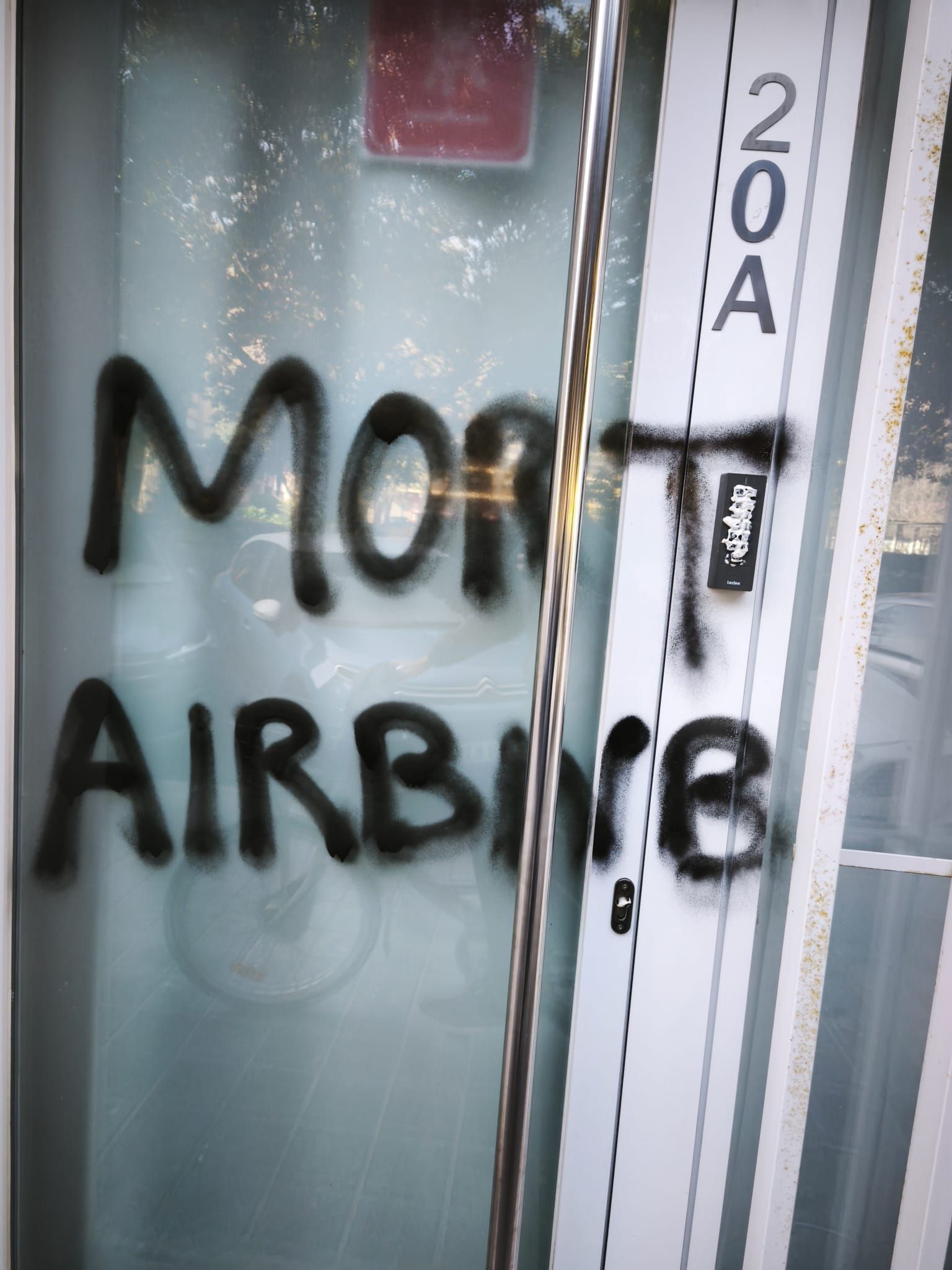 Una pintada y la cerradura destrozada en un apartamento