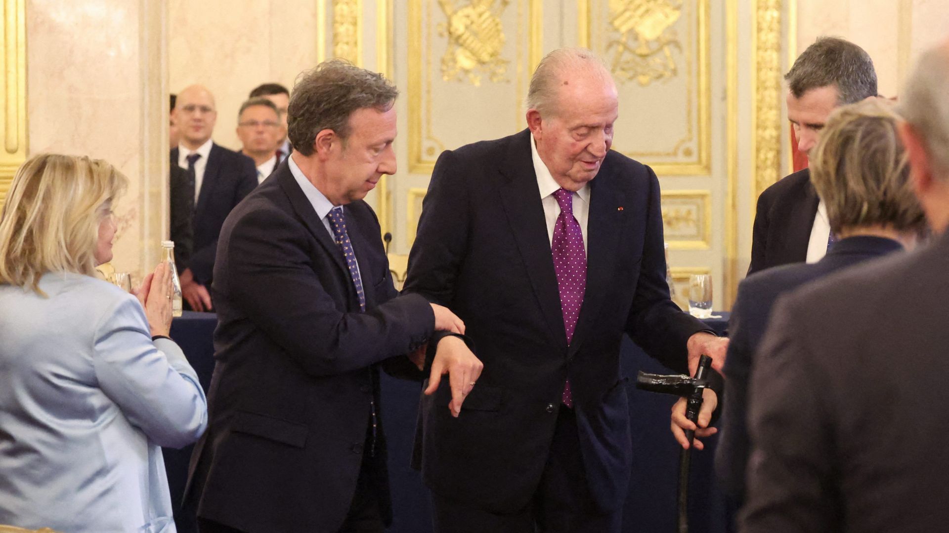 El rey Juan Carlos, asistido al subir al estrado para dar su discurso en la Asamblea Nacional francesa