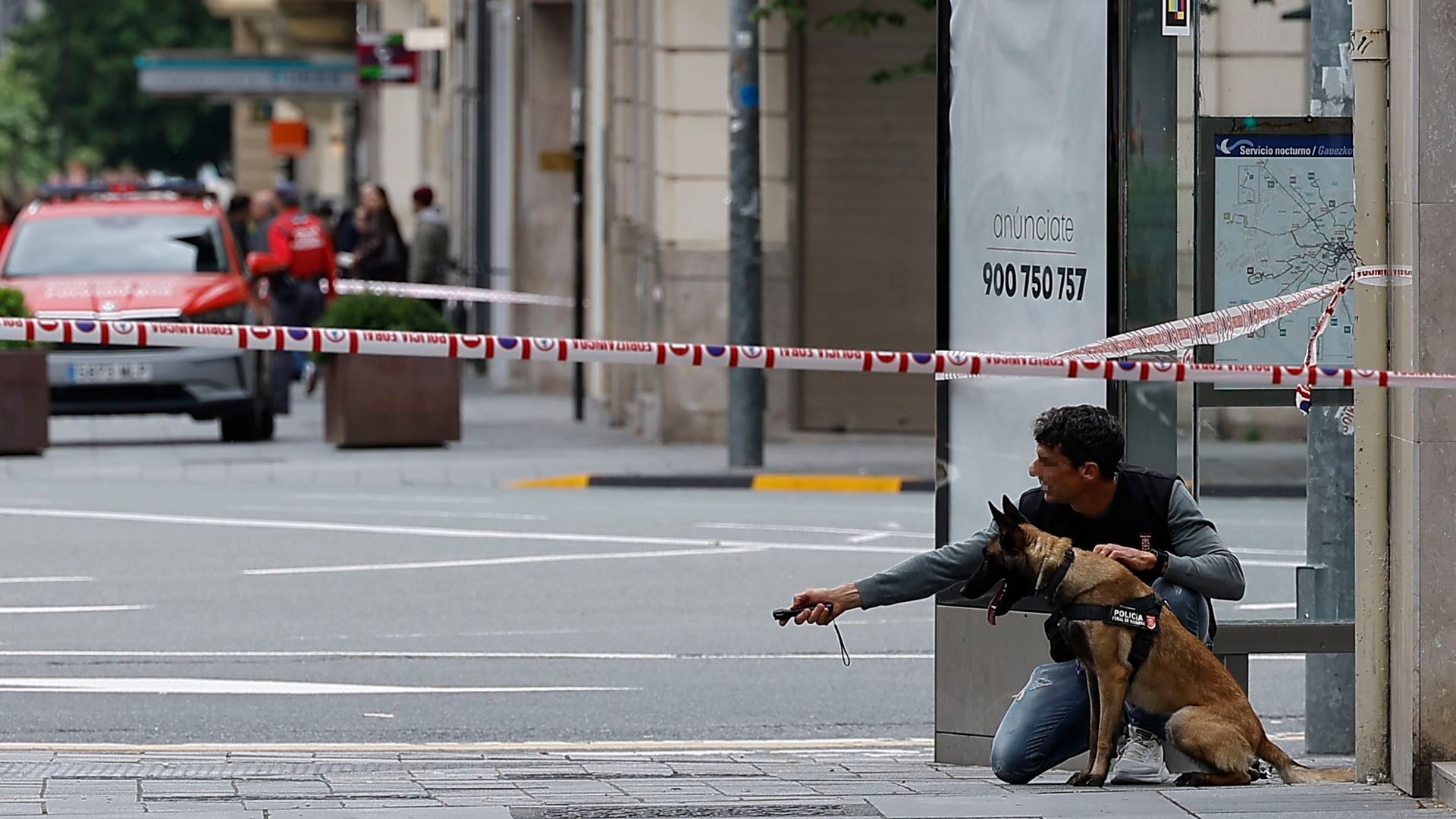 Un miembro de las fuerzas de seguridad y un perro policía desplegados tras encontrarse una maleta abandonada en una parada de autobús en la Plaza de Merindades