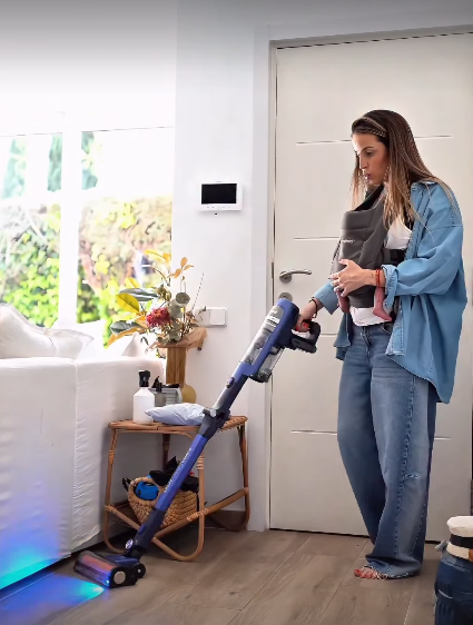 Marta pasando la aspirado con su hija en el porteo