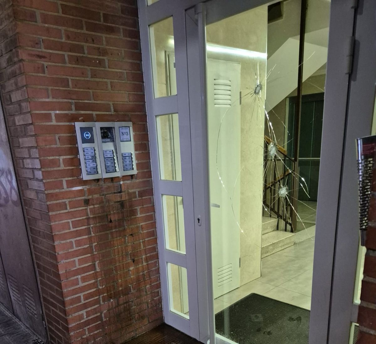 El cristal de la puerta del portal roto a martillazos
