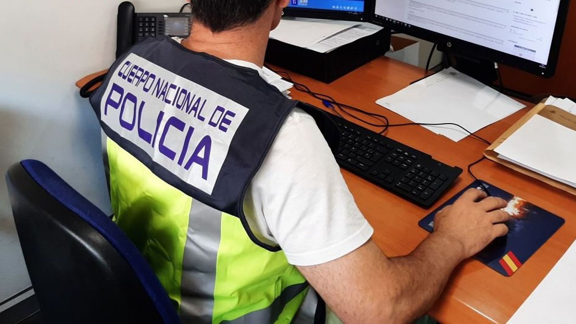 Agente investigando con ordenadores en comisaría Agente investigando con ordenadores en comisaría