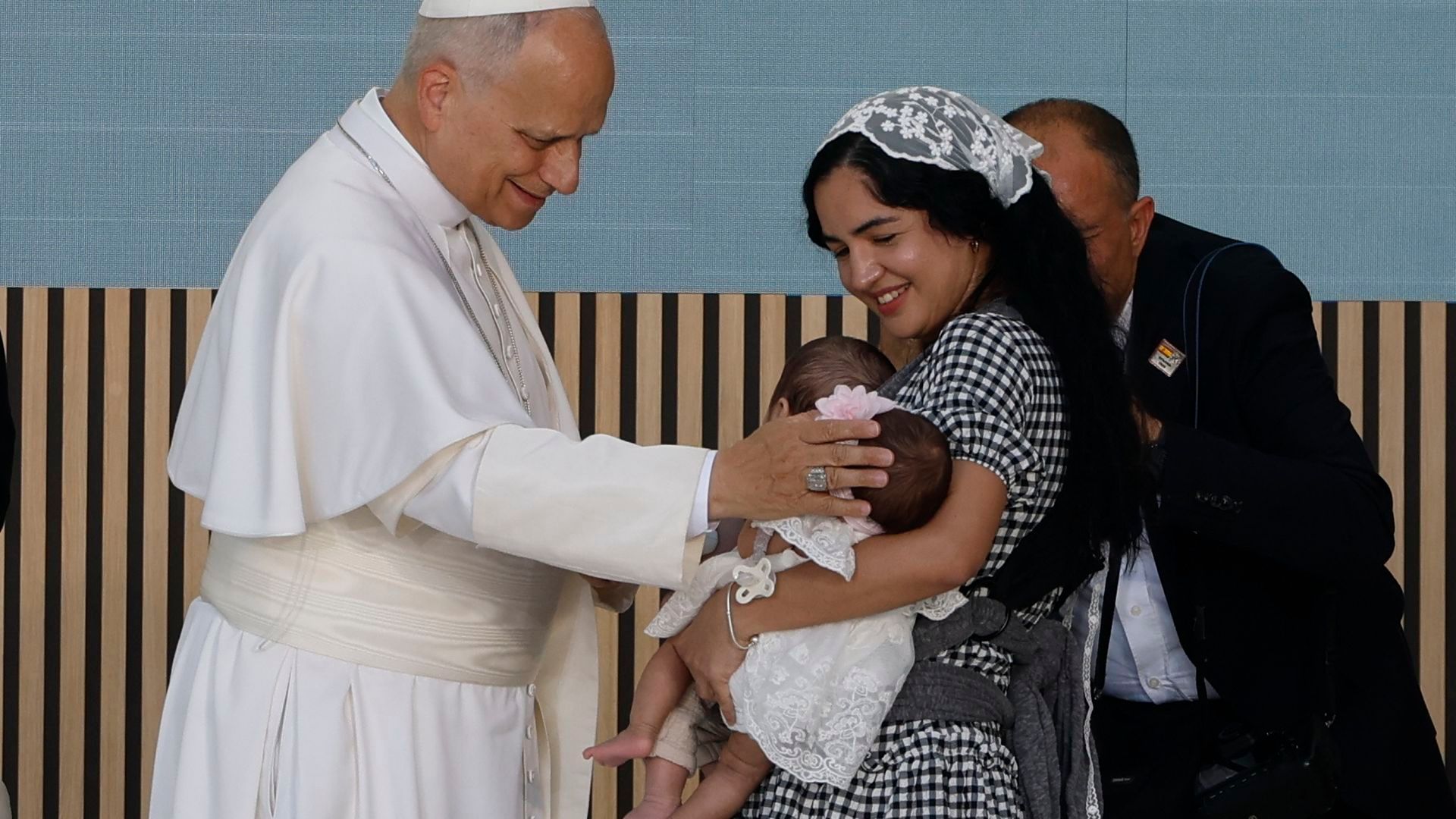 El papa da la bendición a los dos gemelos de una madre migrante