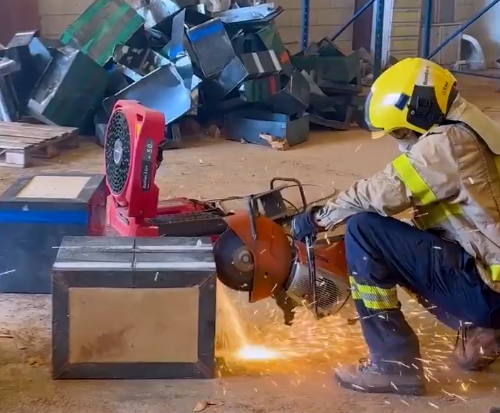 Un bombero cortando una de las cajas metálicas