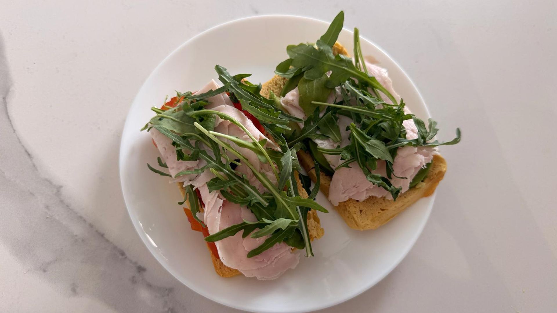 Tostada de pan de garbanzo con rúcola, aguacate y tomate