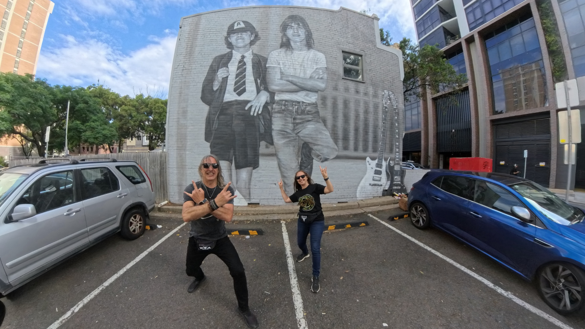 Marta y Héctor posan con un mural de los hermanos Young