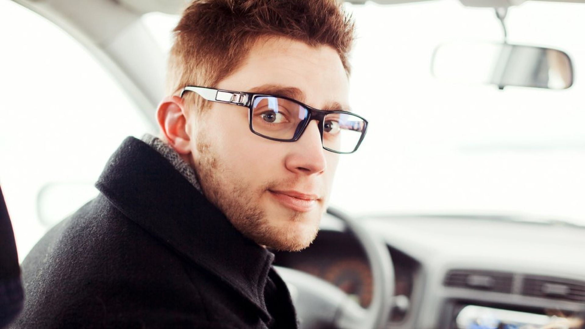 Joven conductor usando gafas al volante Joven conductor usando gafas al volante