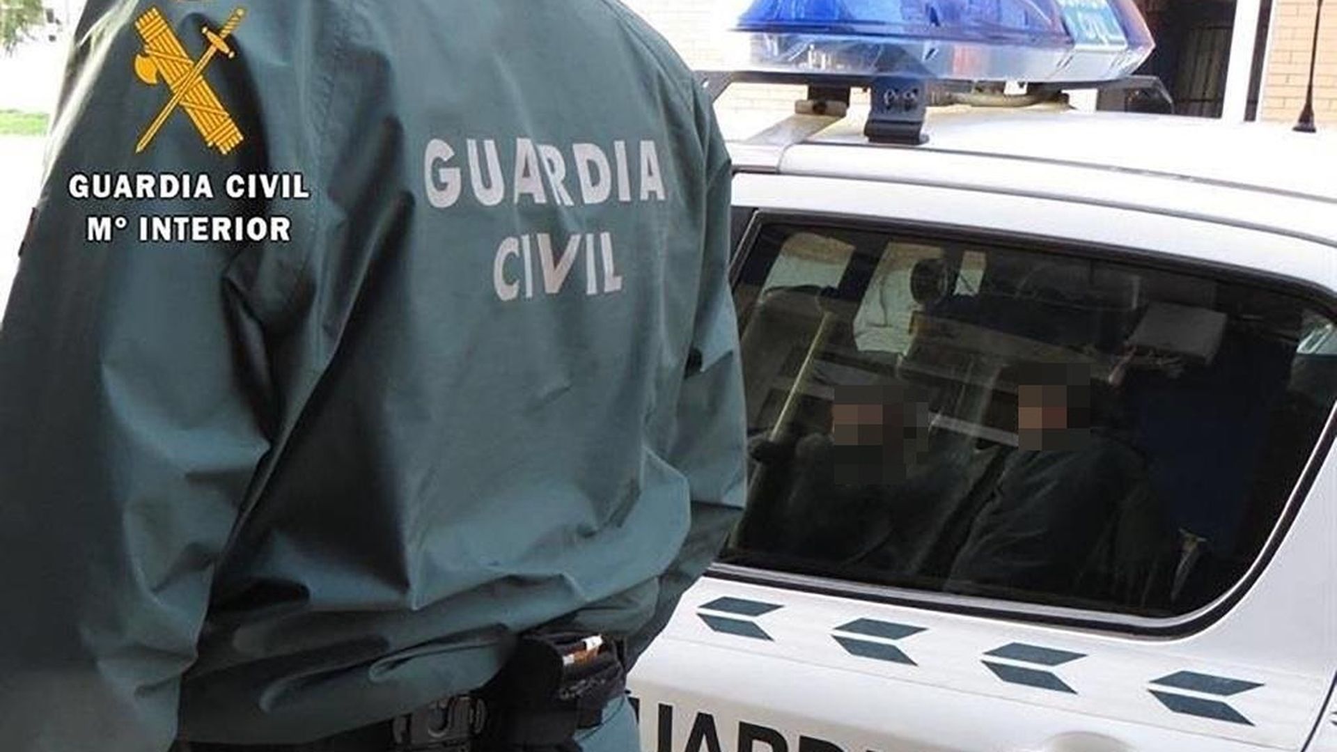 Un agente de la Guardia Civil junto a un coche patrulla Un agente de la Guardia Civil junto a un coche patrulla