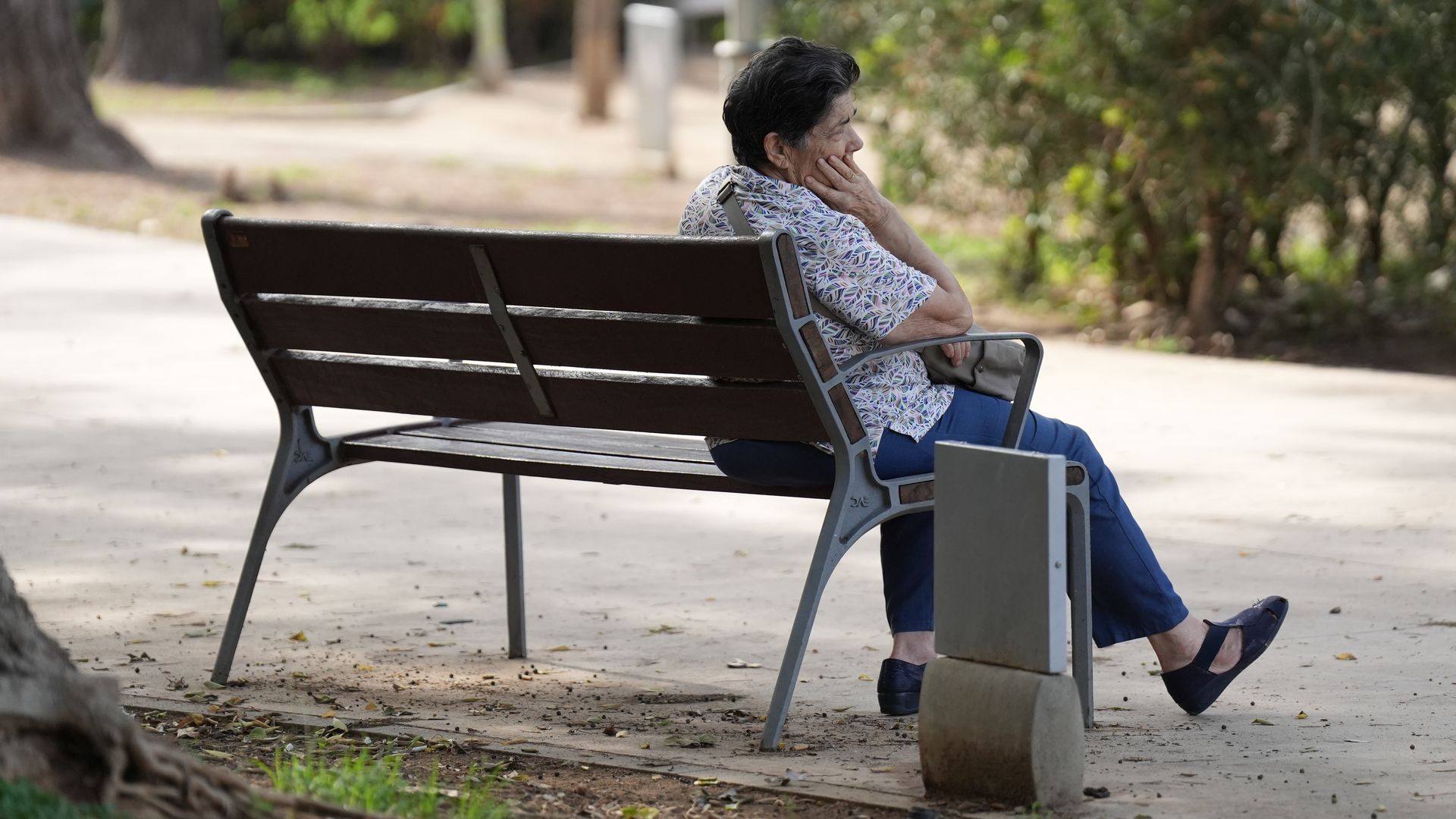 Una persona mayor esperando en un banco Una persona mayor esperando en un banco