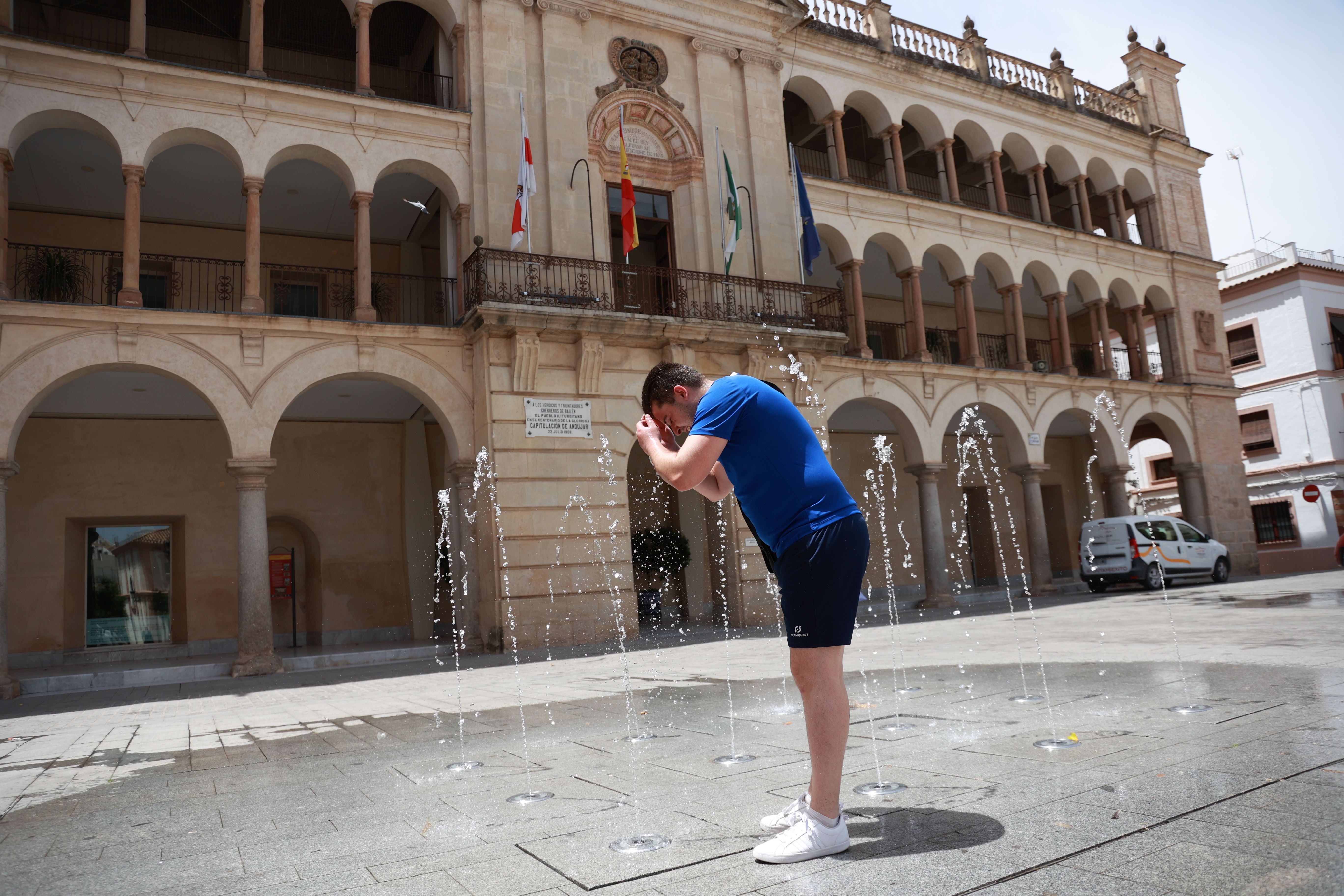 Un joven se refresca con unas fuentes en Andújar, Jaén