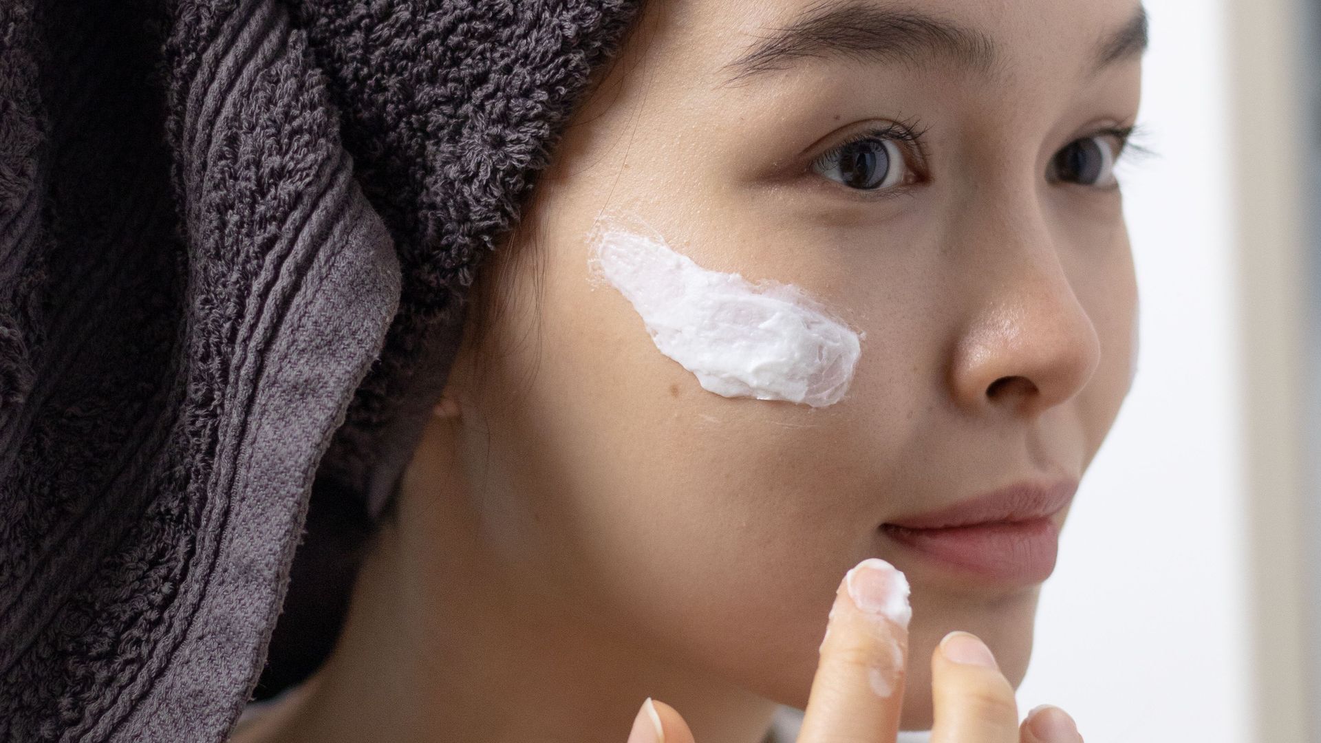Una chica aplicándose crema en la cara Una chica aplicándose crema en la cara