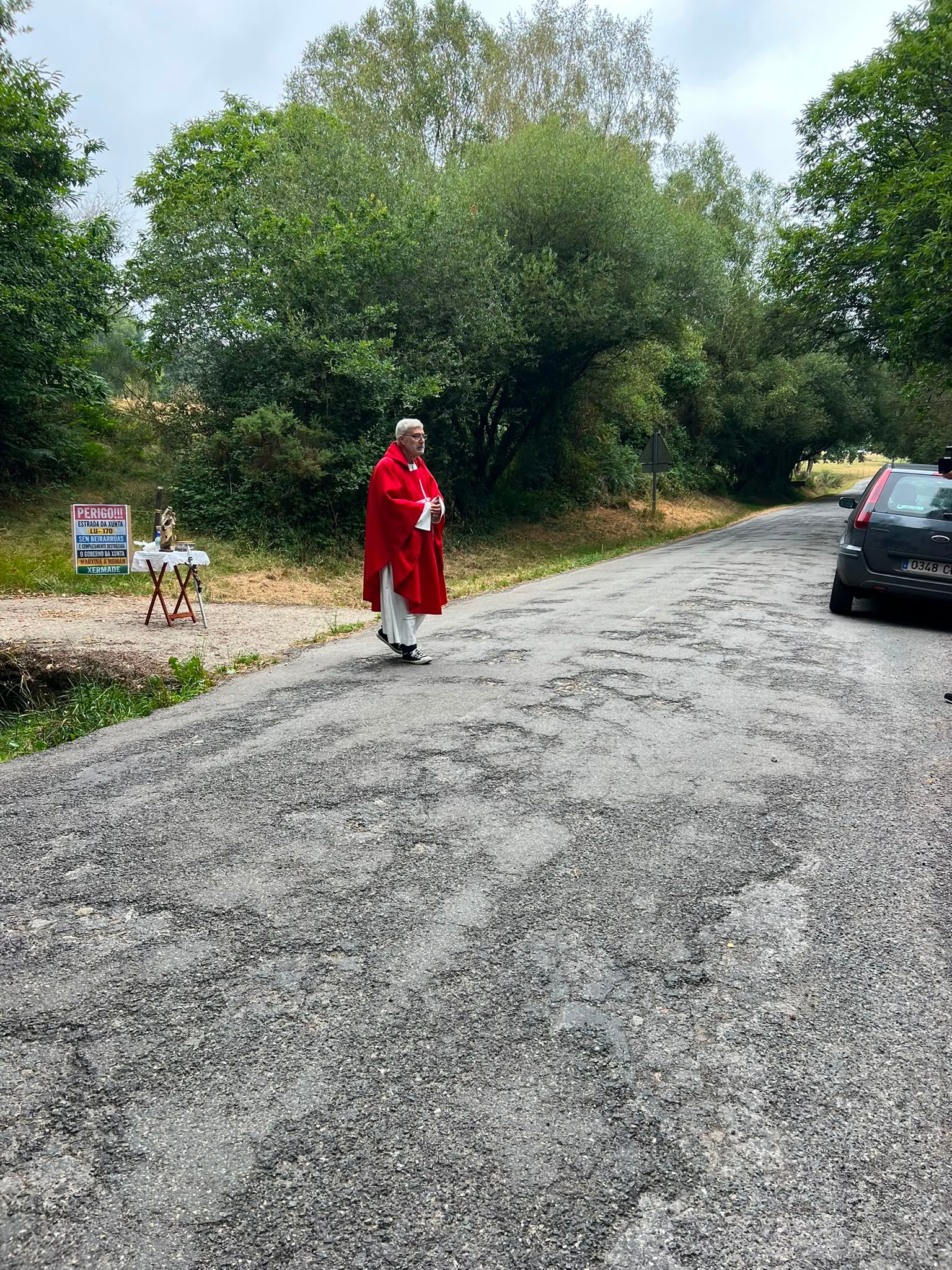 El cura Luis Patiño, de la parroquia de Momán, oficia la misa en la carretera para reivindicar el estado total de abandono