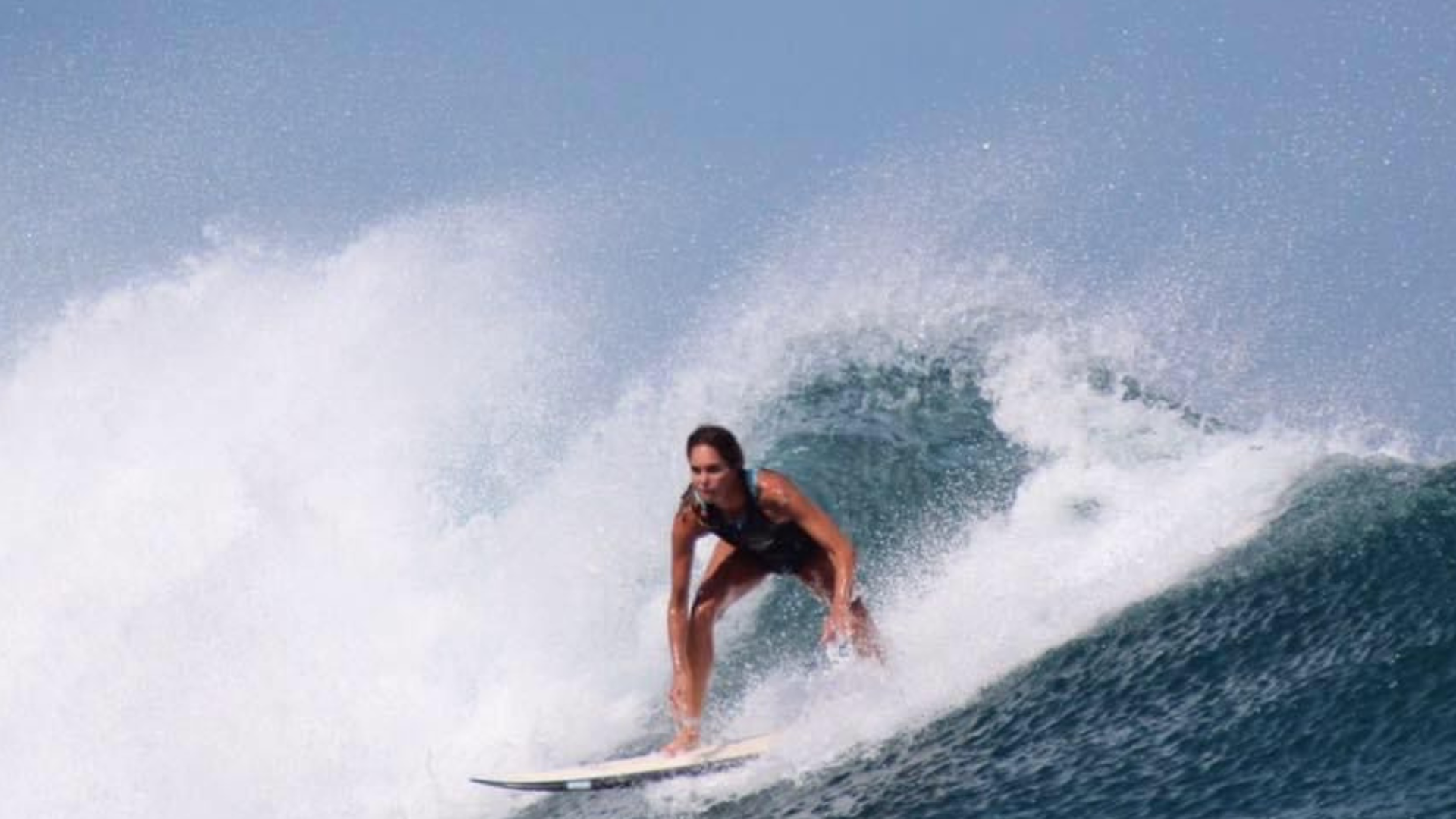 María Palacio, sobre su tabla de surf, disfrutando de una ola
