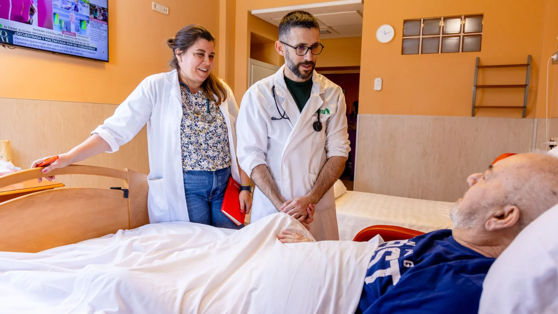 Dos sanitarios atendiendo a un paciente en cuidados paliativos Dos sanitarios atendiendo a un paciente en cuidados paliativos