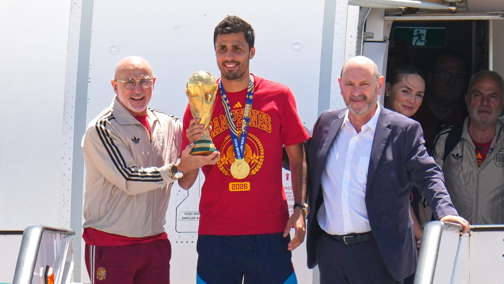 Luis de la Fuente, Rodrigo Hernández y Rafael Louzán posan con el Mundial en su llegada a España