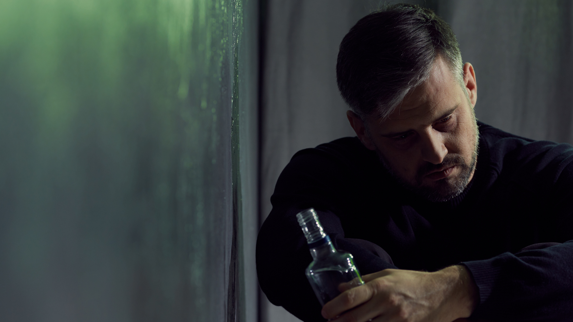 Un hombre se apoya en la pared mientras sostiene una botella Un hombre se apoya en la pared mientras sostiene una botella
