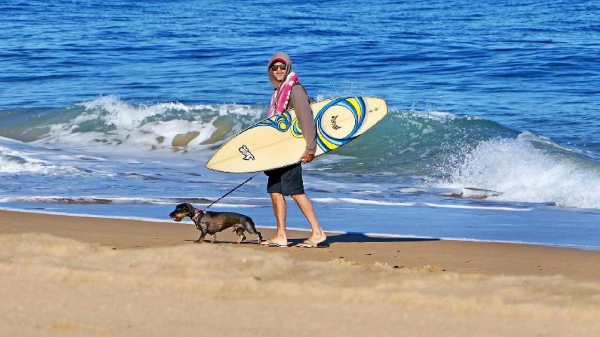 Jose Pellón, con su perro y su tabla de surf, en la orilla del mar