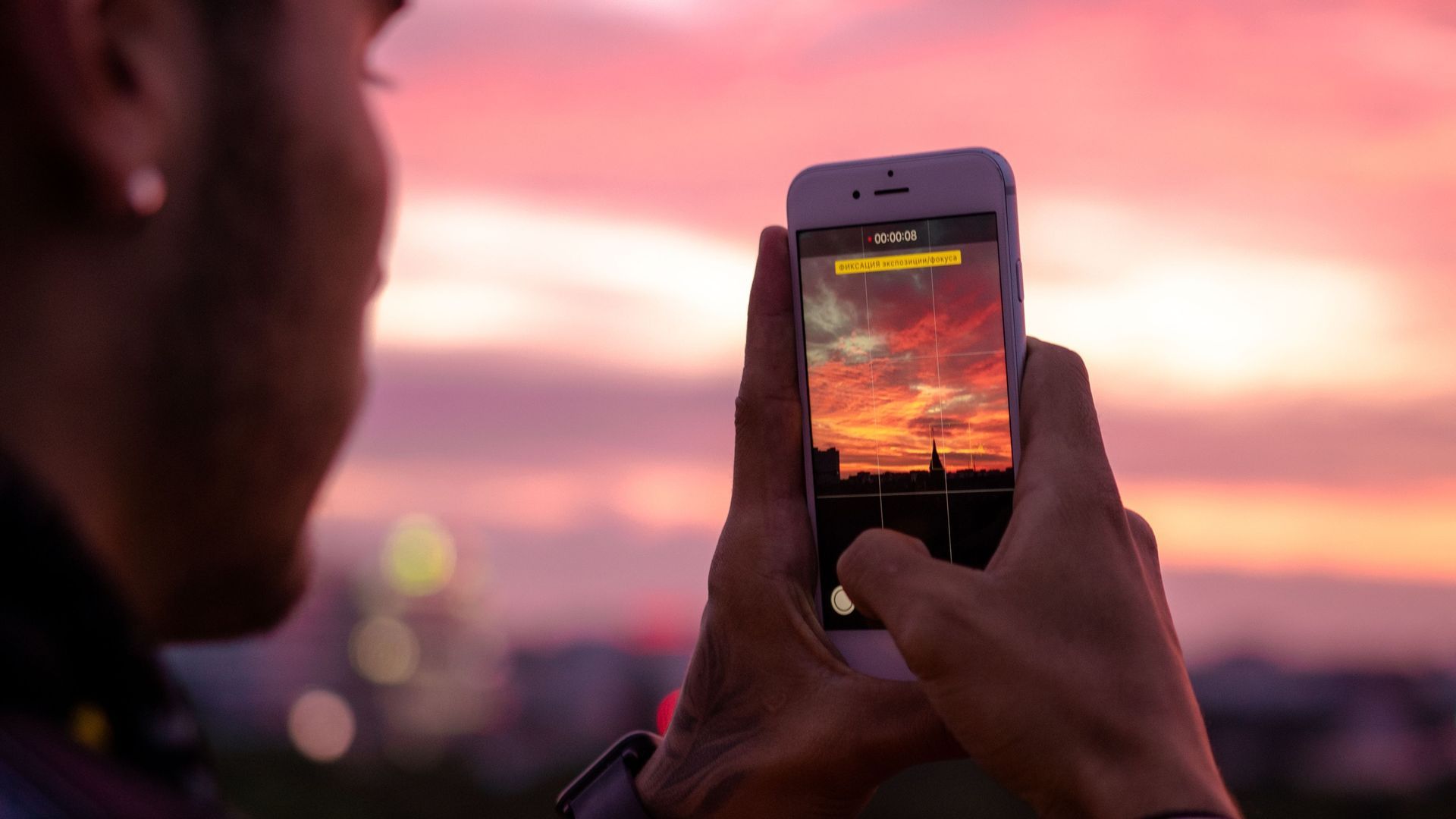 Un chico haciendo un video con la cámara del móvil durante un atardecer Un chico haciendo un video con la cámara del móvil durante un atardecer