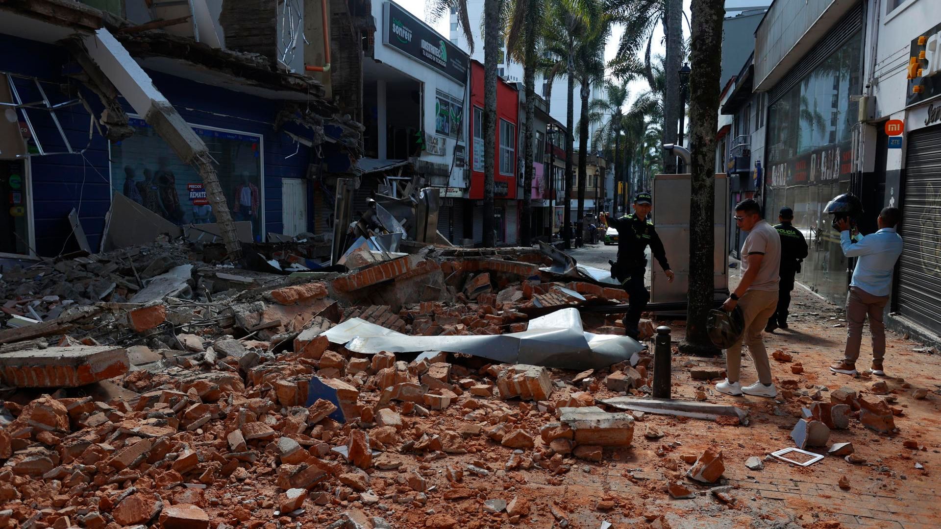 Personas caminan frente a una edificación afectada tras un fuerte temblor este lunes, en Manizales
