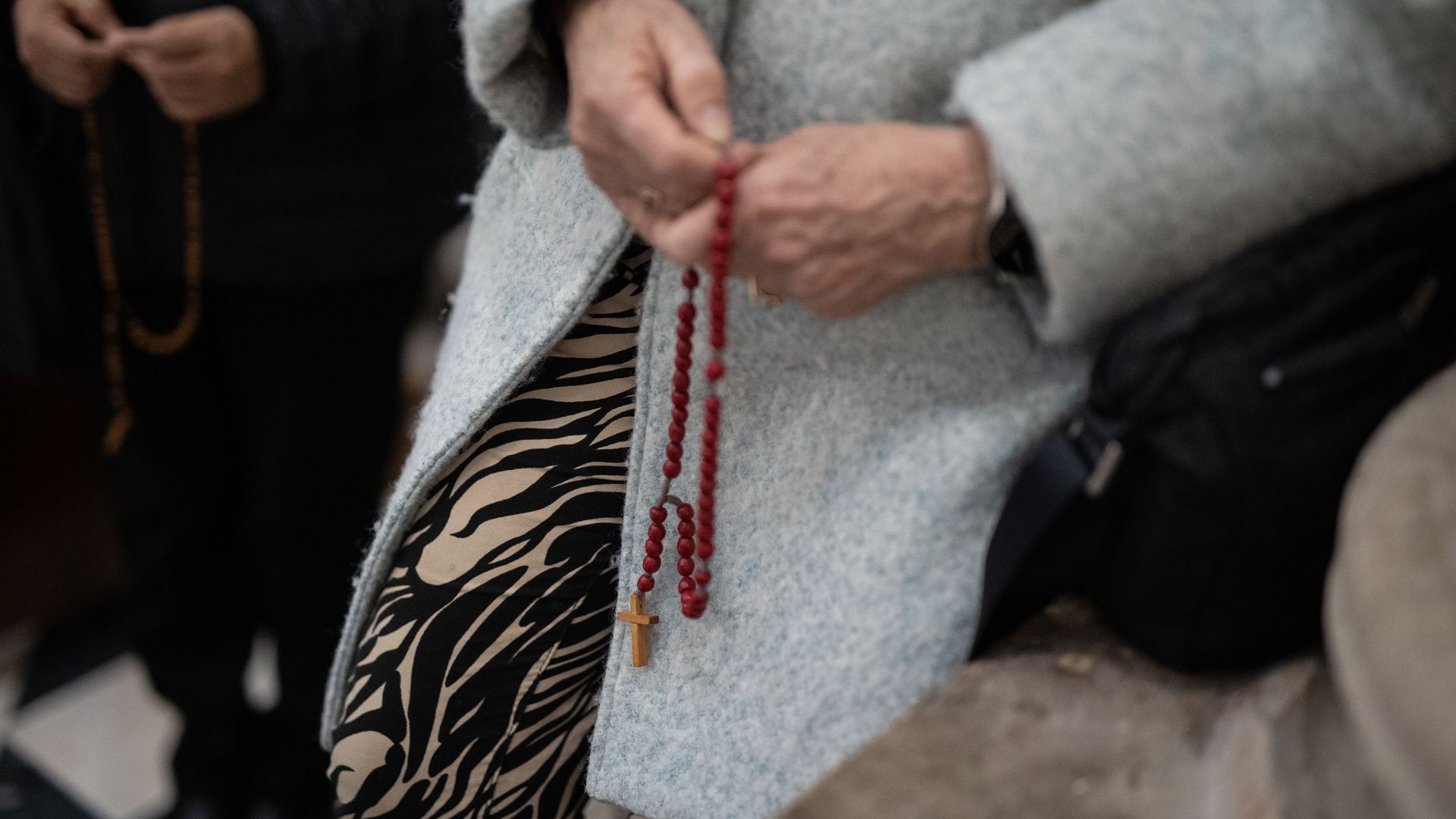 Una mujer reza el rosario en una iglesia Una mujer reza el rosario en una iglesia