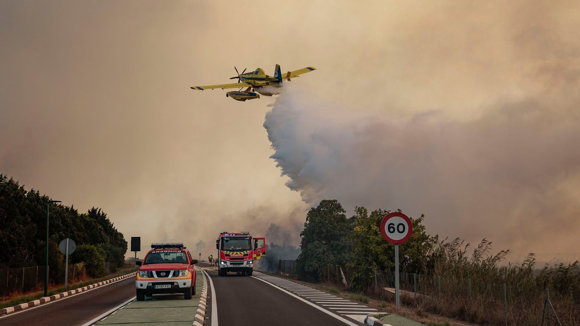 Un hidroavión realiza una descarga de agua sobre la carretera CV-500 ante el avance del incendio forestal declarado este jueves en la Gola de Pujol, dentro de la Devesa Un hidroavión realiza una descarga de agua sobre la carretera CV-500 ante el avance del incendio forestal declarado este jueves en la Gola de Pujol, dentro de la Devesa