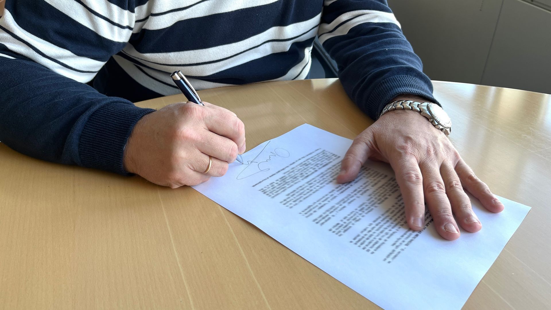 Una persona firma un contrato de trabajo. Una persona firma un contrato de trabajo.