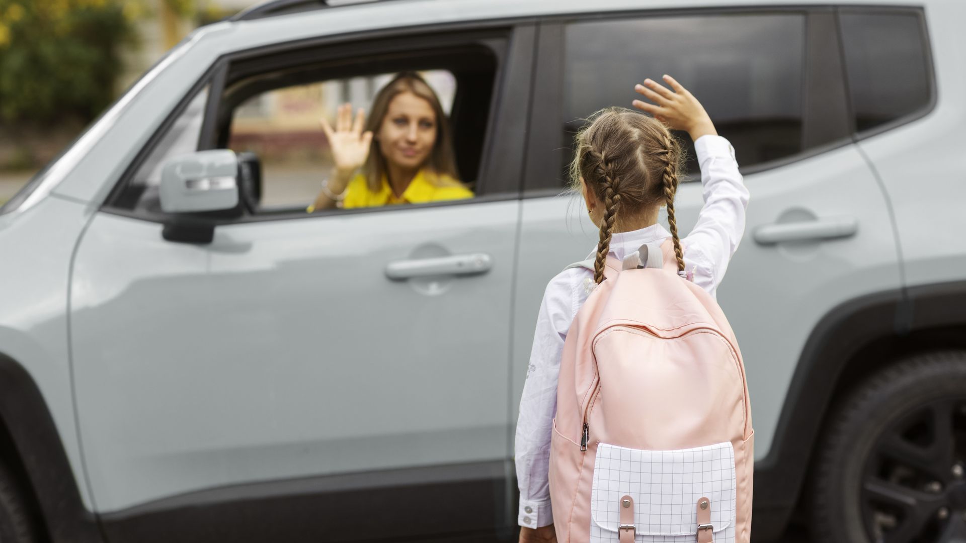 Mujer con el coche en doble fila despidiéndose de su hija que entra al colegio Mujer con el coche en doble fila despidiéndose de su hija que entra al colegio