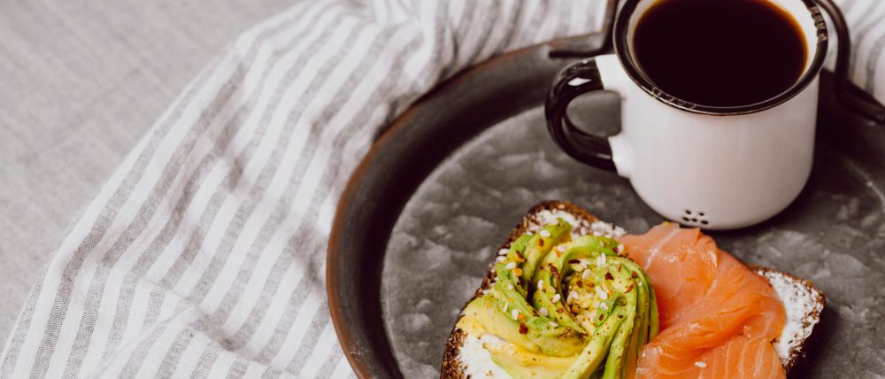 Desayuno saludable con café solo y tostada con salmón y aguacate