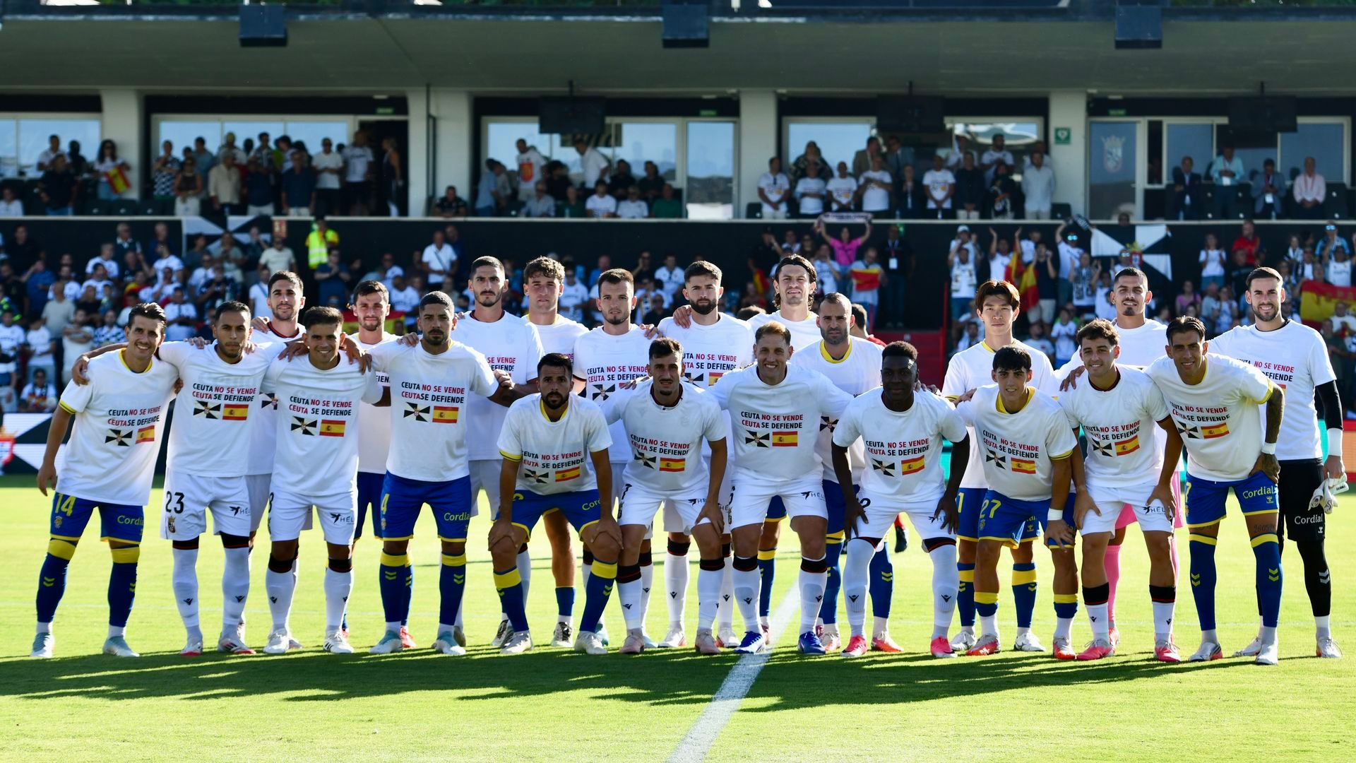 Los jugadores del Ceuta y la UD Las Palmas, con camisetas de apoyo a la ciudad en el Alfonso Murube. Los jugadores del Ceuta y la UD Las Palmas, con camisetas de apoyo a la ciudad en el Alfonso Murube.