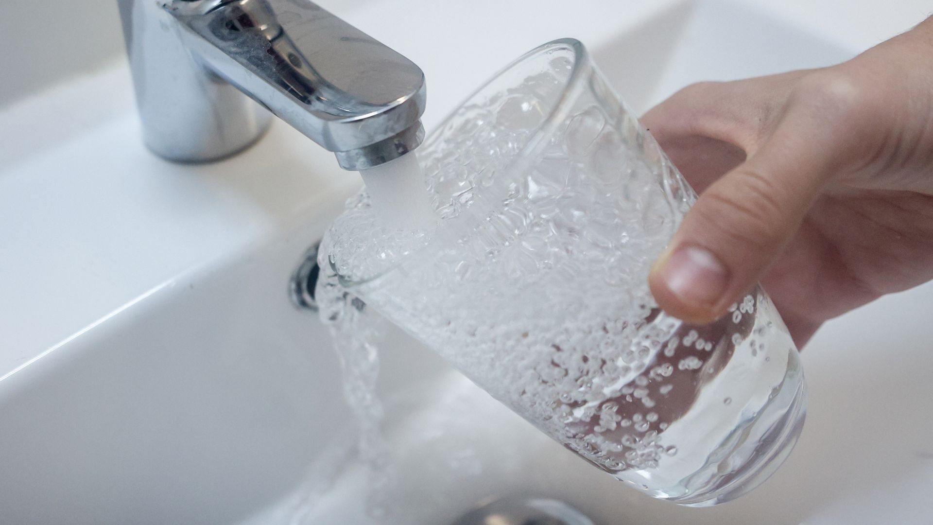 Una persona lleva un vaso de agua en el grifo Una persona lleva un vaso de agua en el grifo