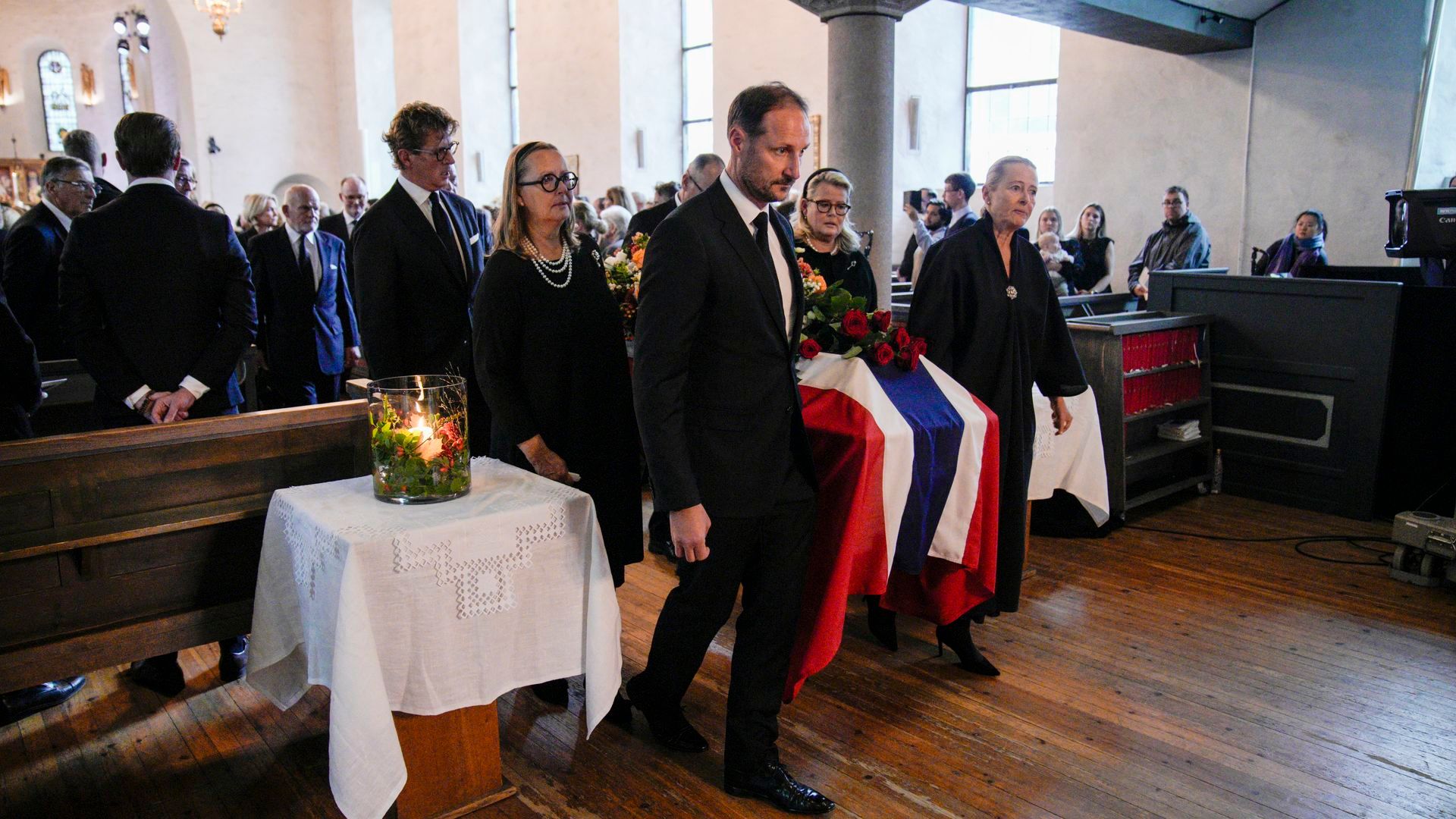 El rey Haakon VIII camina al frente mientras sacan el féretro durante la procesión fúnebre de la princesa Astrid