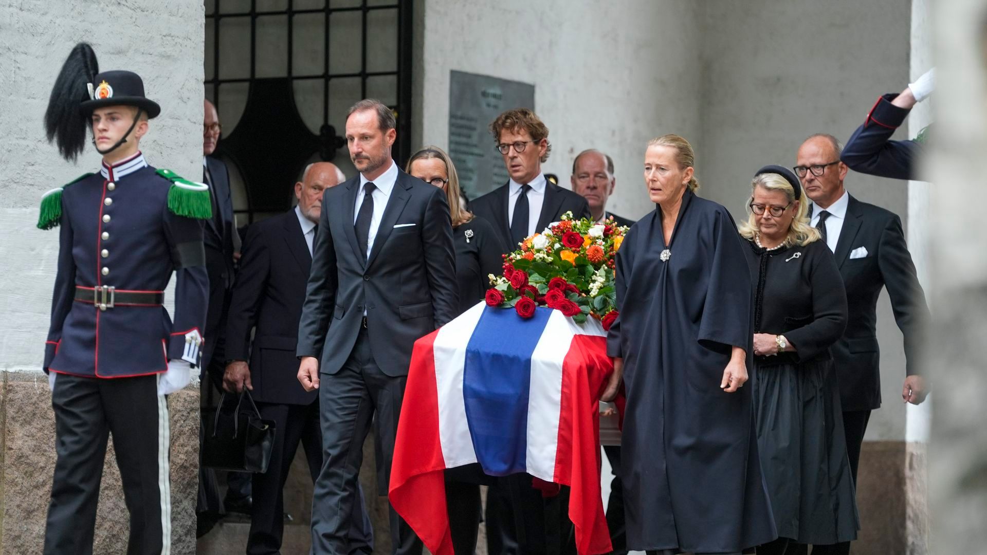 El rey Haakon VIII camina al frente mientras sacan el féretro durante la procesión fúnebre de la princesa Astrid