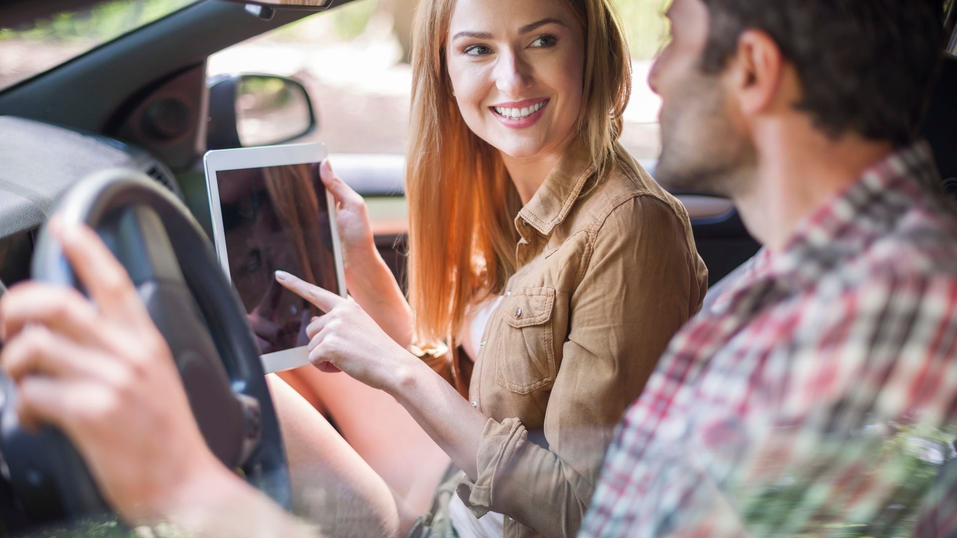 Una pareja en un coche mirando una tablet Una pareja en un coche mirando una tablet