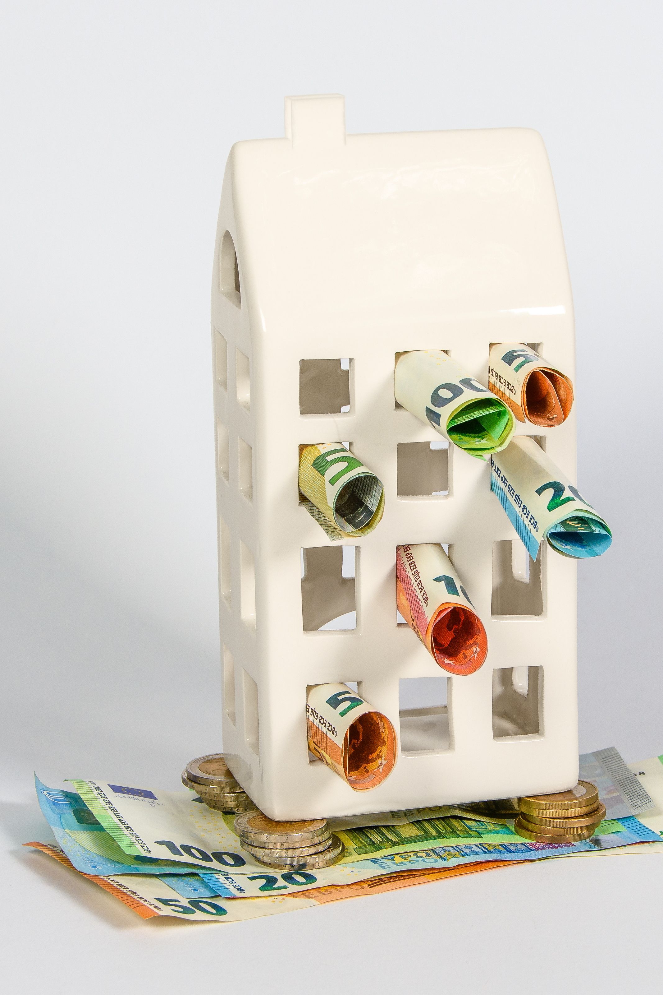 Casa de porcelana con ventanas llenas de billetes como concepto de ahorro doméstico